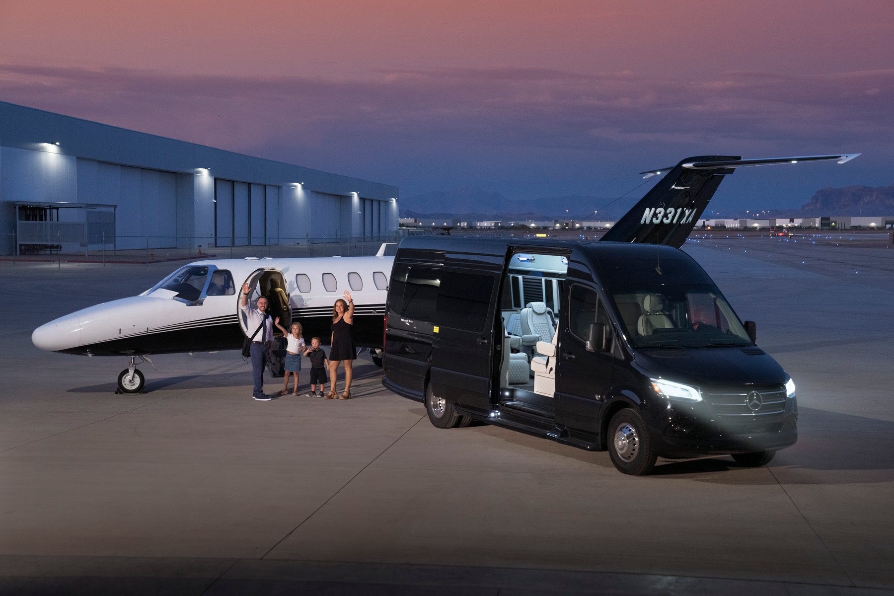 A family arriving to their charter flight at dusk, executive jet and Sprinter on the ramp